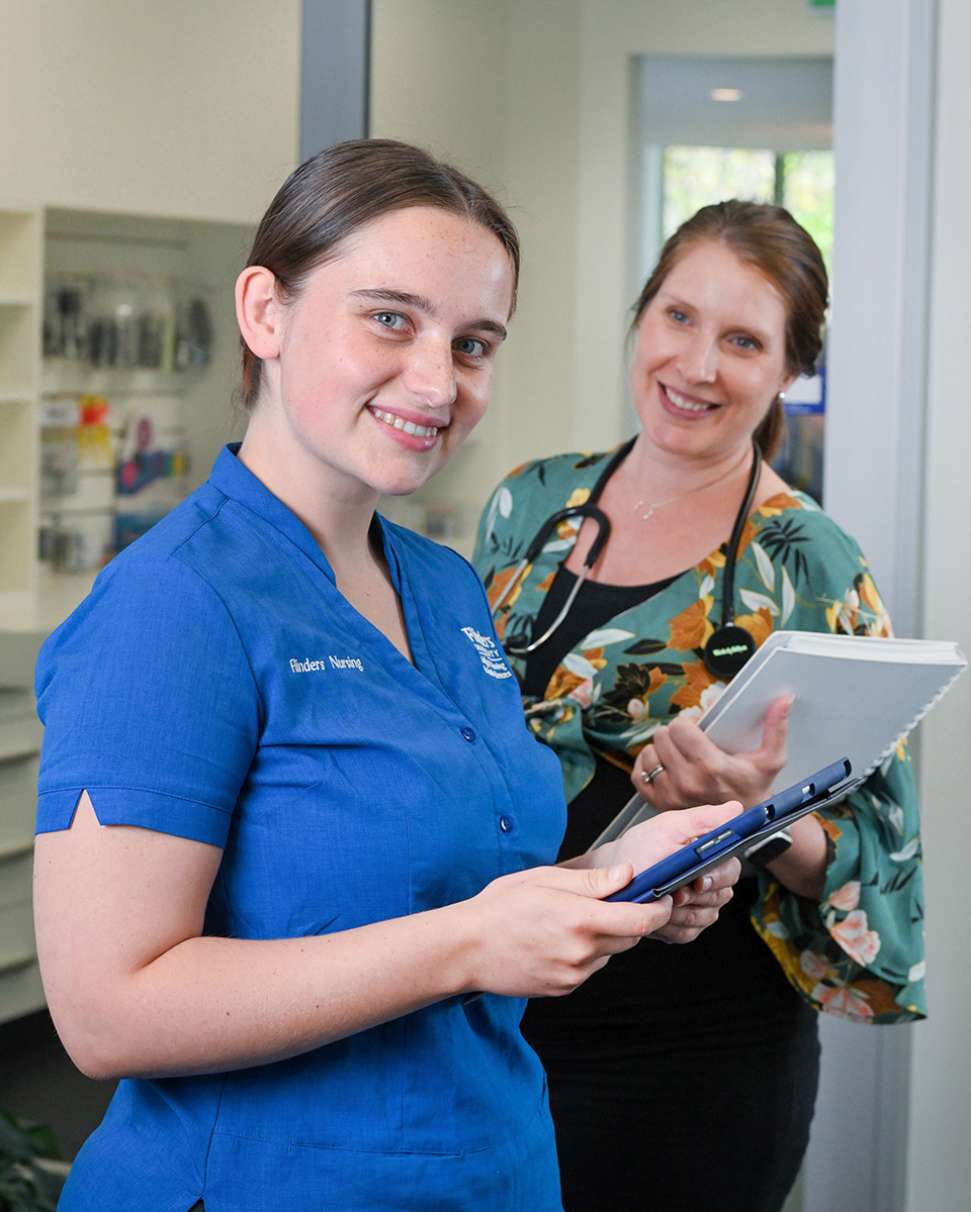 Flinders Nursing Student smiling and holding ipad with nurse stood behind her