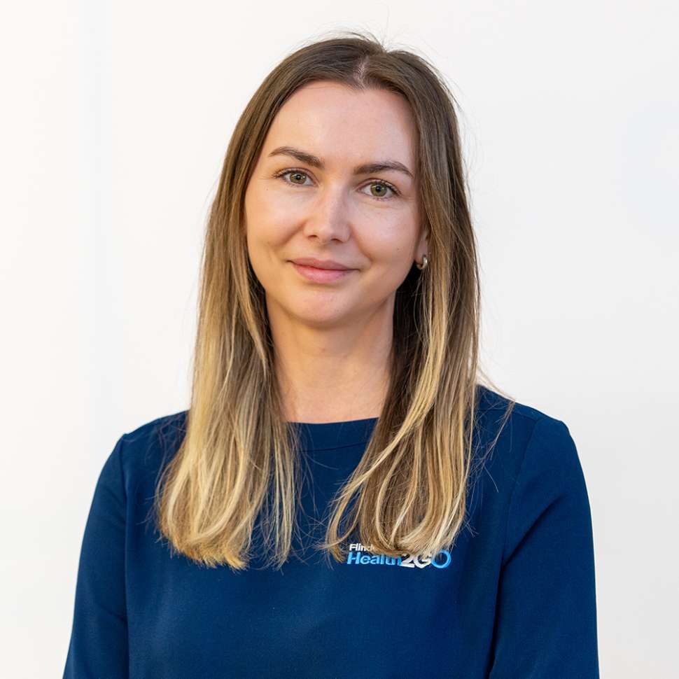 A woman wearing a navy shirt behind a white backdrop