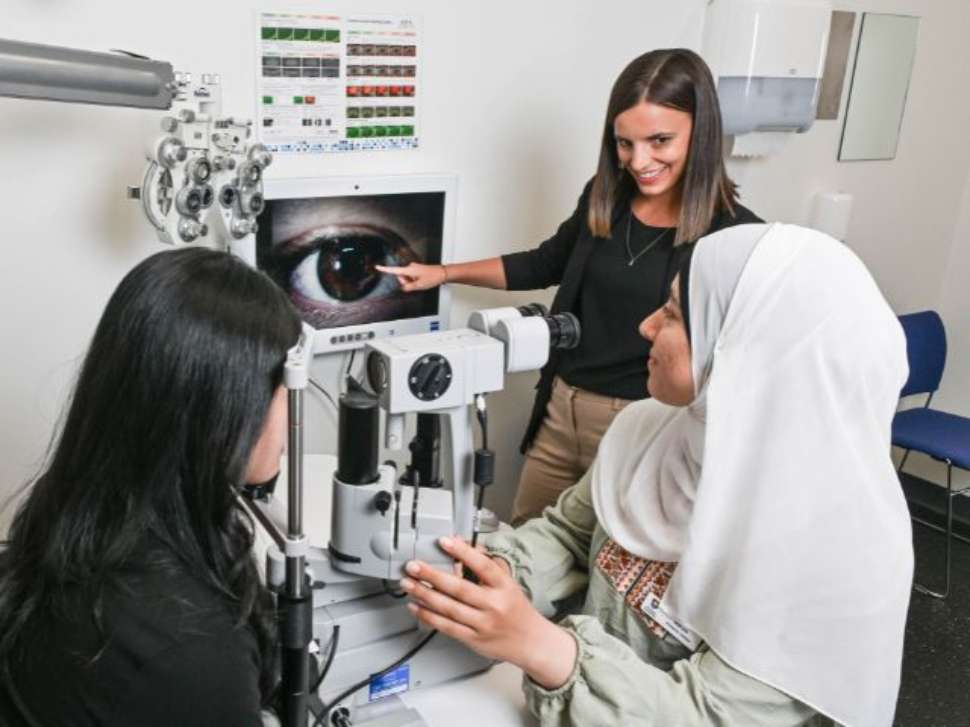 Flinders Optometry Student with clinician looking at eye results from test