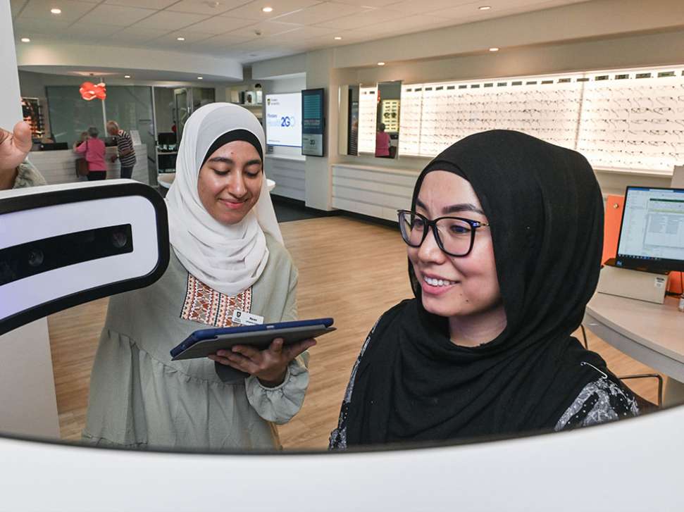 Flinders Optometry Student helping patient in an automated machine to check glasses fit