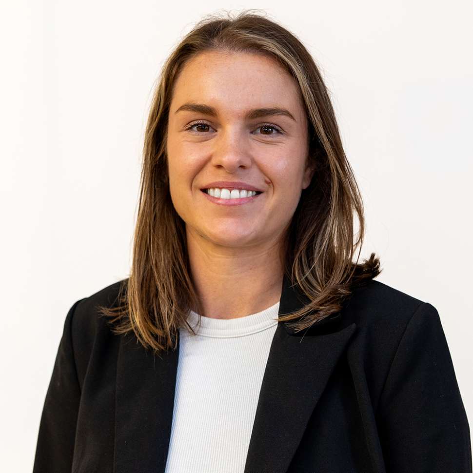 Smiling woman in a black blazer in front of a white backdrop