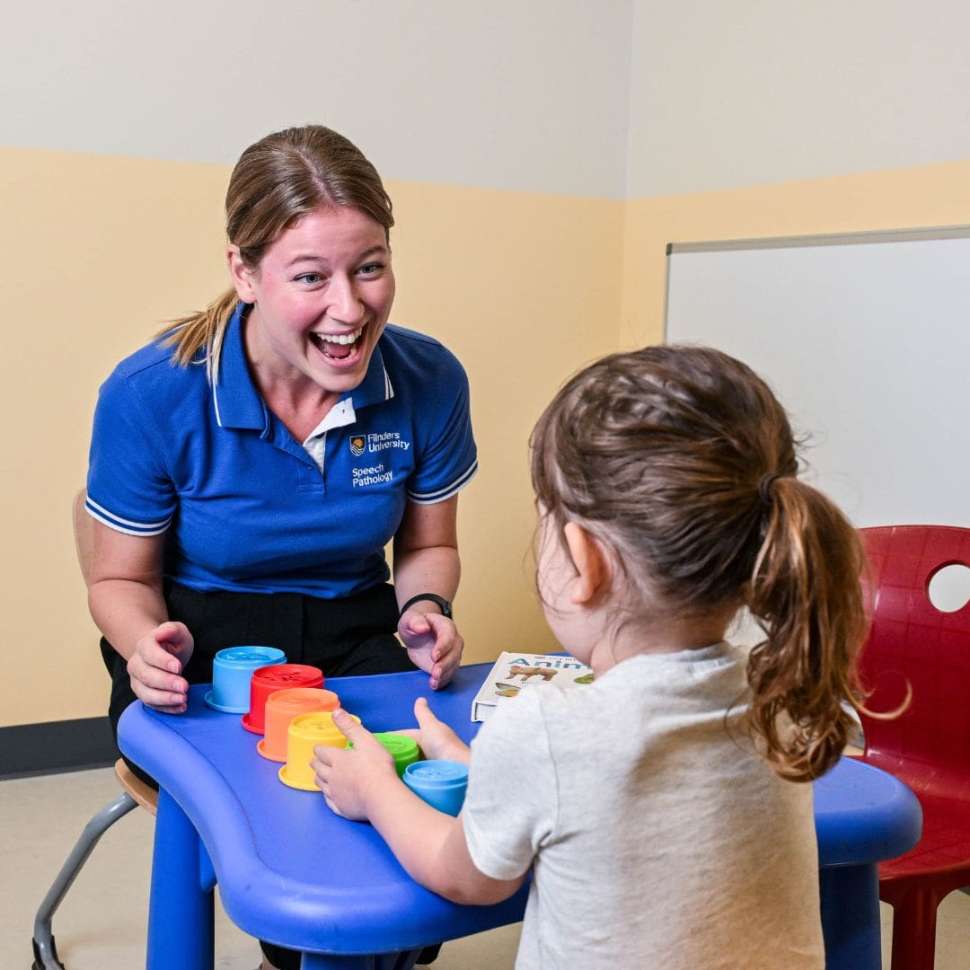 Flinders Speech Pathology Student smiling at child with colourful toy on table between them