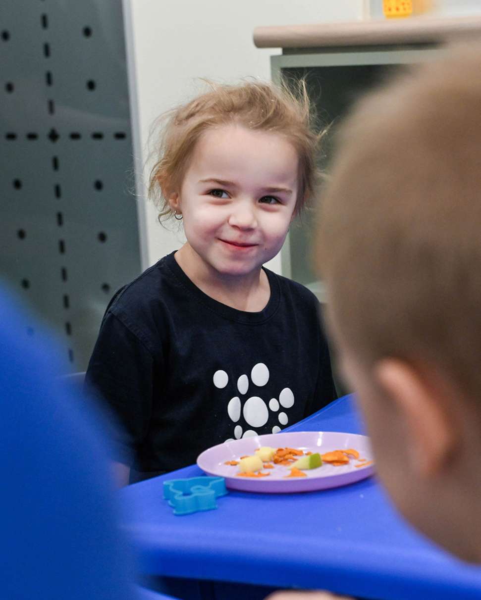 Child smiling with a plate of food in front of them