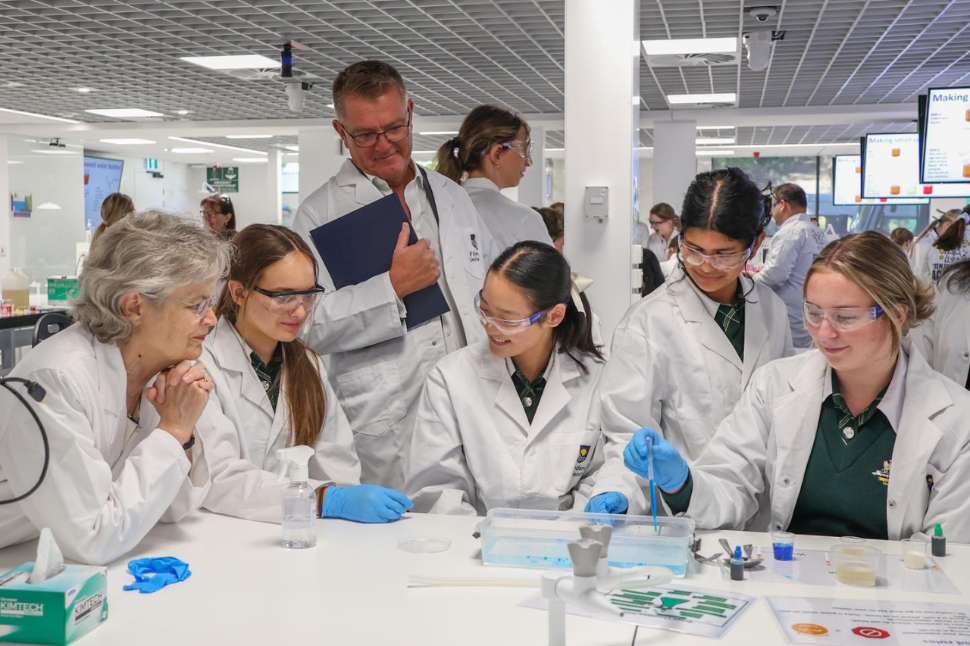 Year 9 girls in a group wearing white lab coats with the University's VC 
