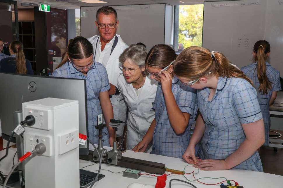 3 year 9 girls doing an experiment at a STEM event with the VC watching