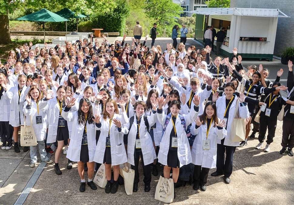 Year 9 girls in a group wearing white lab coats celebrating