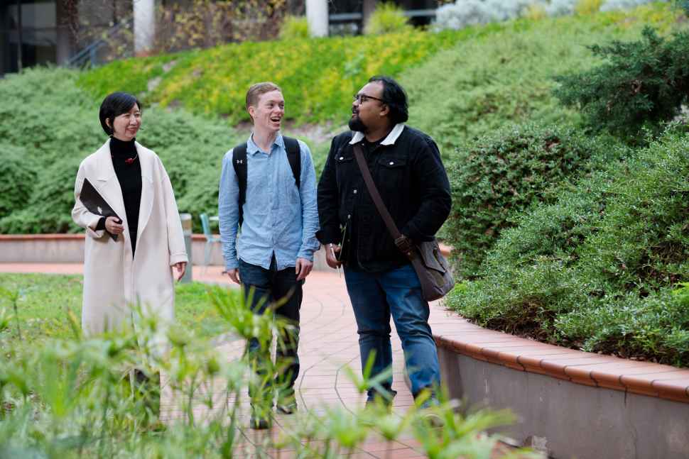 Two social work students walking with lecturer on campus